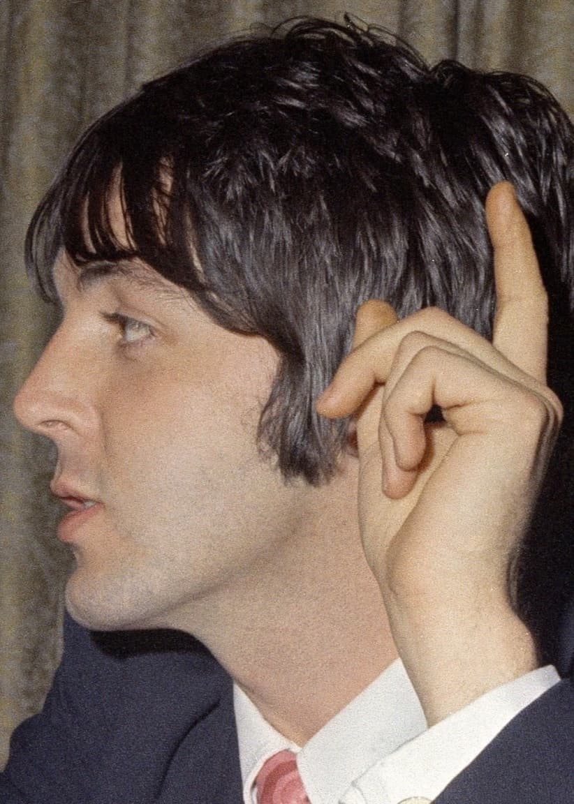 Man ser Paul McCartney från axlarna och uppåt men bara från vänster sida. Han håller upp handen med tydligt fingervisning av pekfingret. Han ser ut att bära kavaj, skjorta och slips.