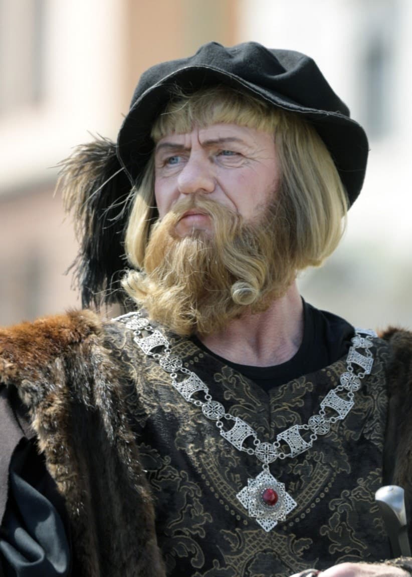 Person klädd som Gustav Vasa, med historisk dräkt i mörka färger och pälsdetaljer, samt en dekorativ kedja runt halsen.