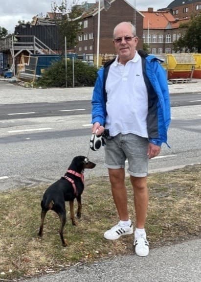 Tomas Östergren står vid en trafikerad väg i Trelleborg med sin hund Kira.