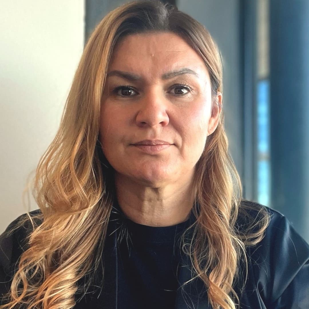 Josipa Kesic, reporter på P4 Göteborg, står inomhus vid ett fönster med utsikt över moderna byggnader och grönska i bakgrunden.