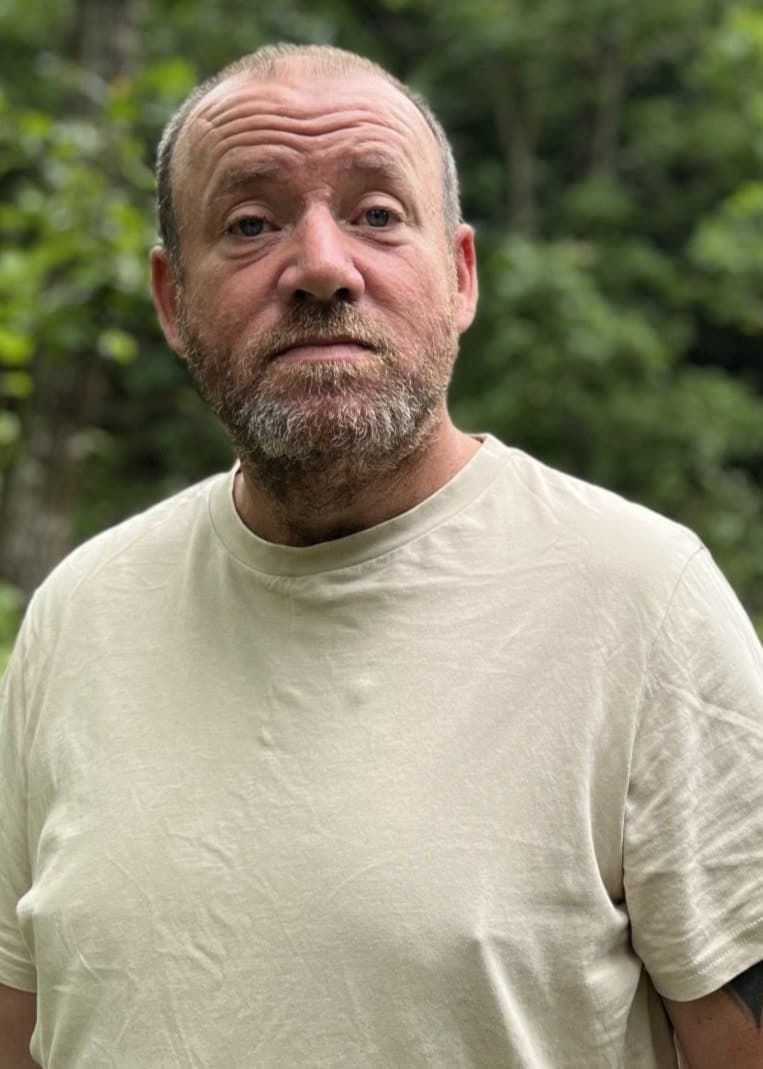 Patrik Magnusson står på en grusväg omgiven av lummig grönska i Emmaboda. Han bär en ljus t-shirt.