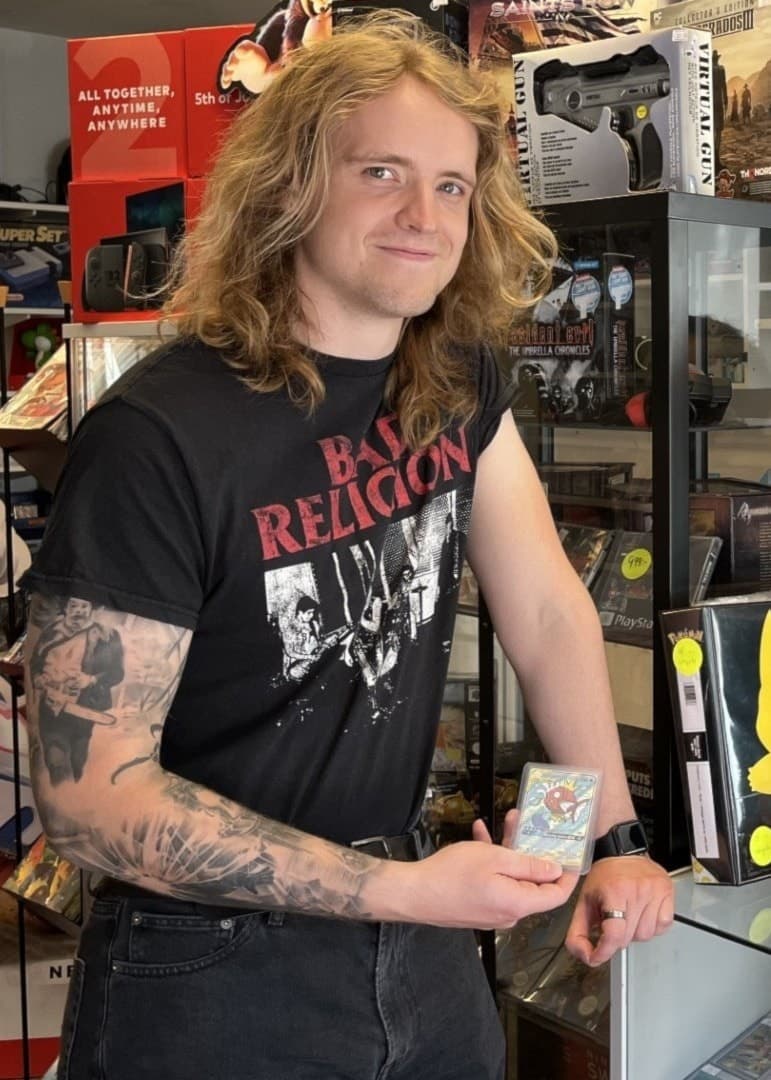 Felix Norén och Patrik Svalstedt står i en butik fylld med samlarobjekt och retrospel. En av dem håller i ett samlarkort medan de samtalar vid en glasmonter med fler objekt.