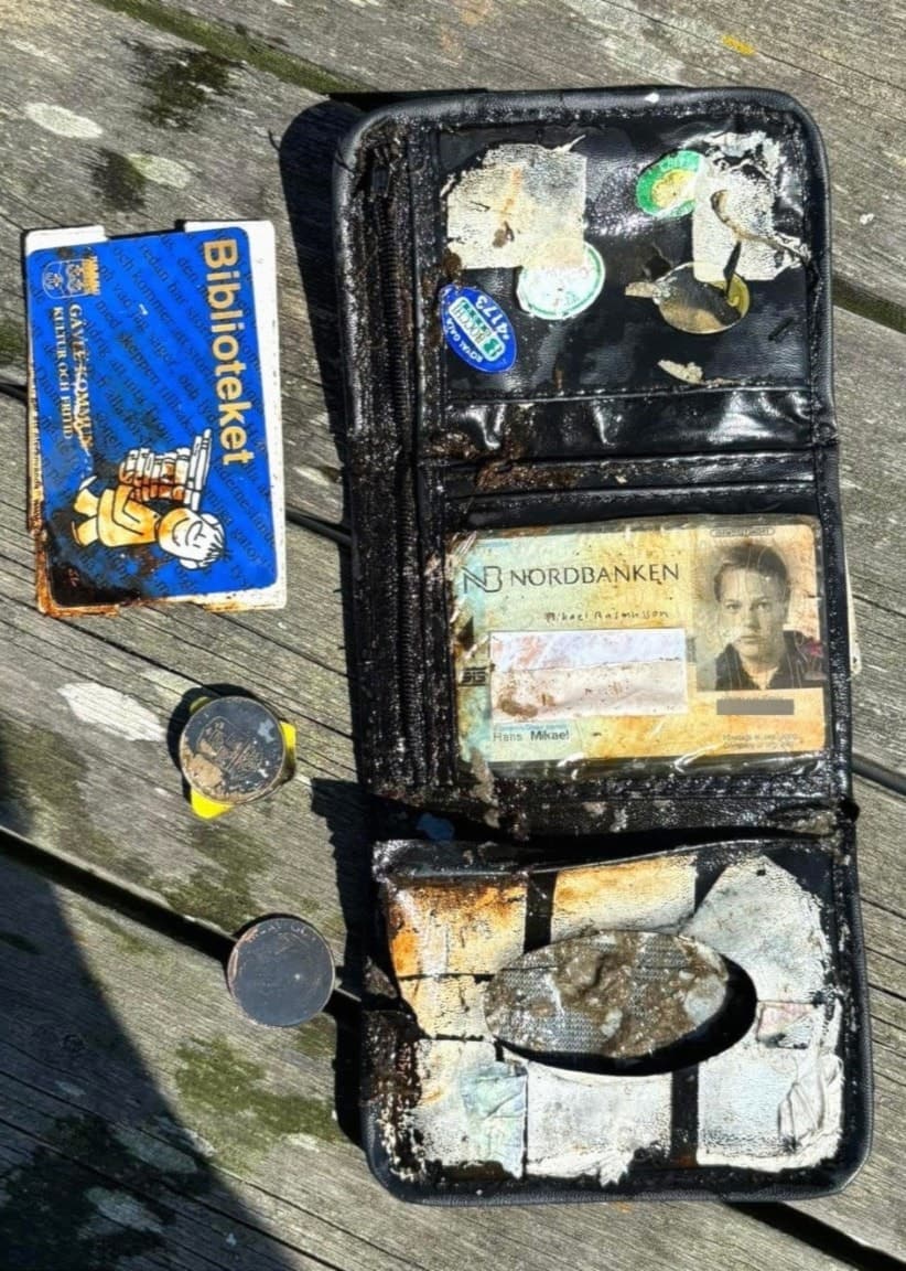 Mikael Rasmusson står utomhus vid en Storsjön omgiven av skog. Han bär en mörk t-shirt med tryck och bakgrunden visar en lugn, naturnära miljö med vatten och träd + Mikaels borttappade slitna plånbok ligger öppen på en träyta, innehållande mynt, sedlar, ett bibliotekskort med namnet Mikael synligt samt ett bankkort.