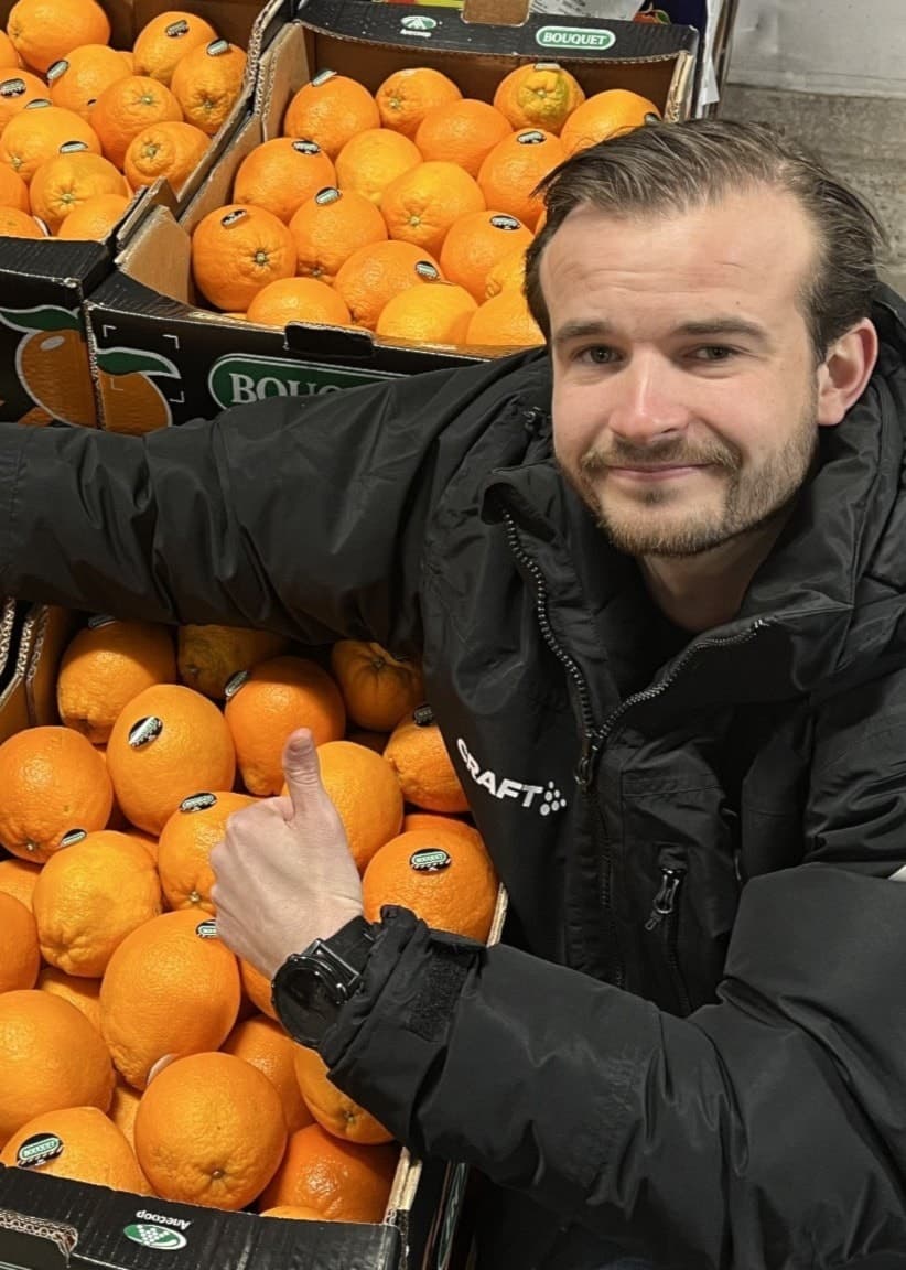 Man står vid flera pallar med apelsiner.