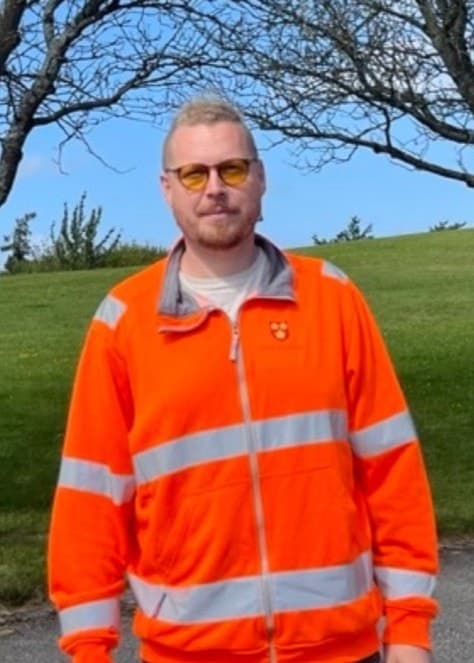 Jon Springe, samordnare på gatu- och parkenheten i Svedala, står framför förgiftade träd med vissna grenar. En skylt på ett träd informerar om skadan och pågående utredning.