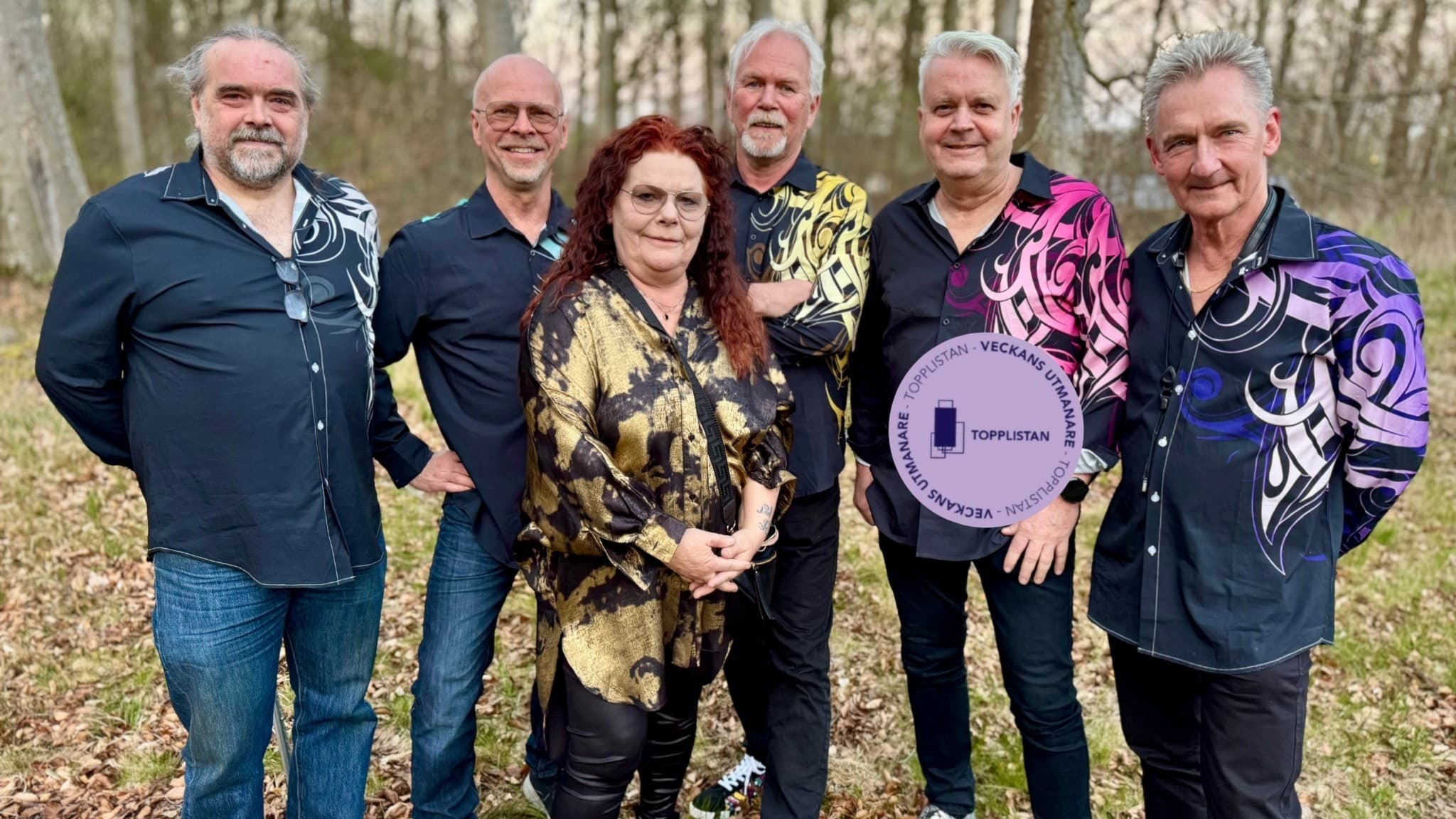 Gruppfoto av Sillabandet, klädda i färgglada skjortor och stående utomhus på en gräsbevuxen plats med träd i bakgrunden. Bandet är kända för sin musik på Topplistan.