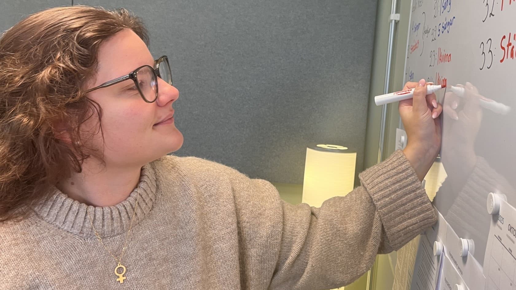 Kvinna skriver på whiteboard-tavla