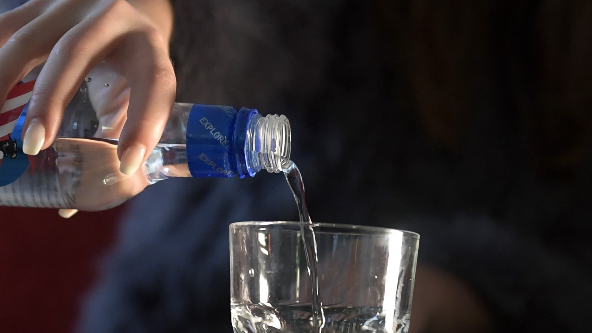 En tonårsflicka häller upp vodka från en blå flaska i ett dricksglas. Bilden symboliserar ungdomars alkoholkonsumtion och riskerna kring alkoholbruk bland unga i Sverige.