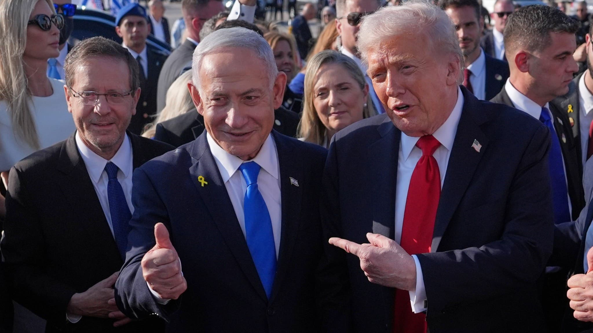 Donald Trump och Israels premiärminister Benjamin Netanyahu står bredvid varandra i en folkmassa. Netanyahu håller upp en tumme medan Trump pekar mot honom. De är omgivna av säkerhetspersonal.
